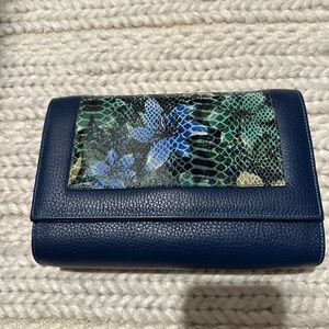 Leather blue with flower leather. Has a gold chain attached